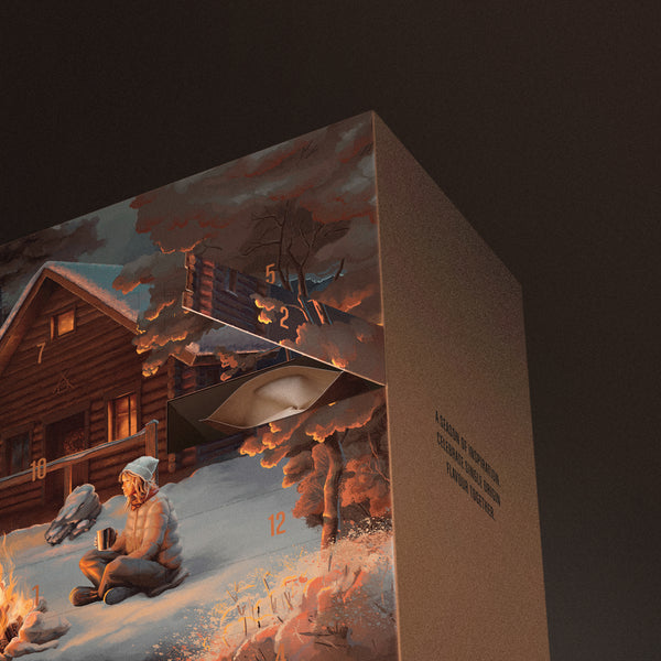 Coffee Advent Calendar box with a winter scene illustration featuring a person by a fire and a cabin.