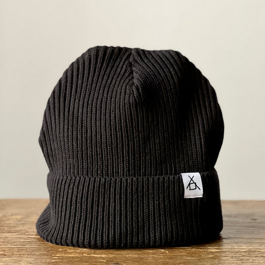 The Barn organic vegan cotton beanie in black with a folded cuff and a small tag with the company logo
