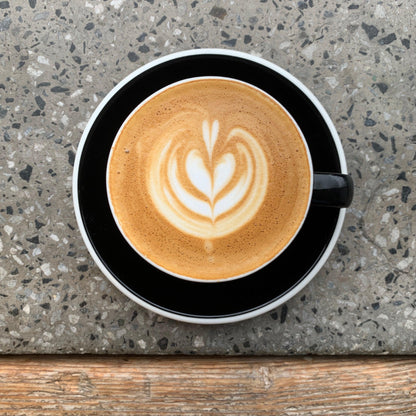 Overhead view of a ceramic espresso cup filled with latte art design made of steamed milk on top