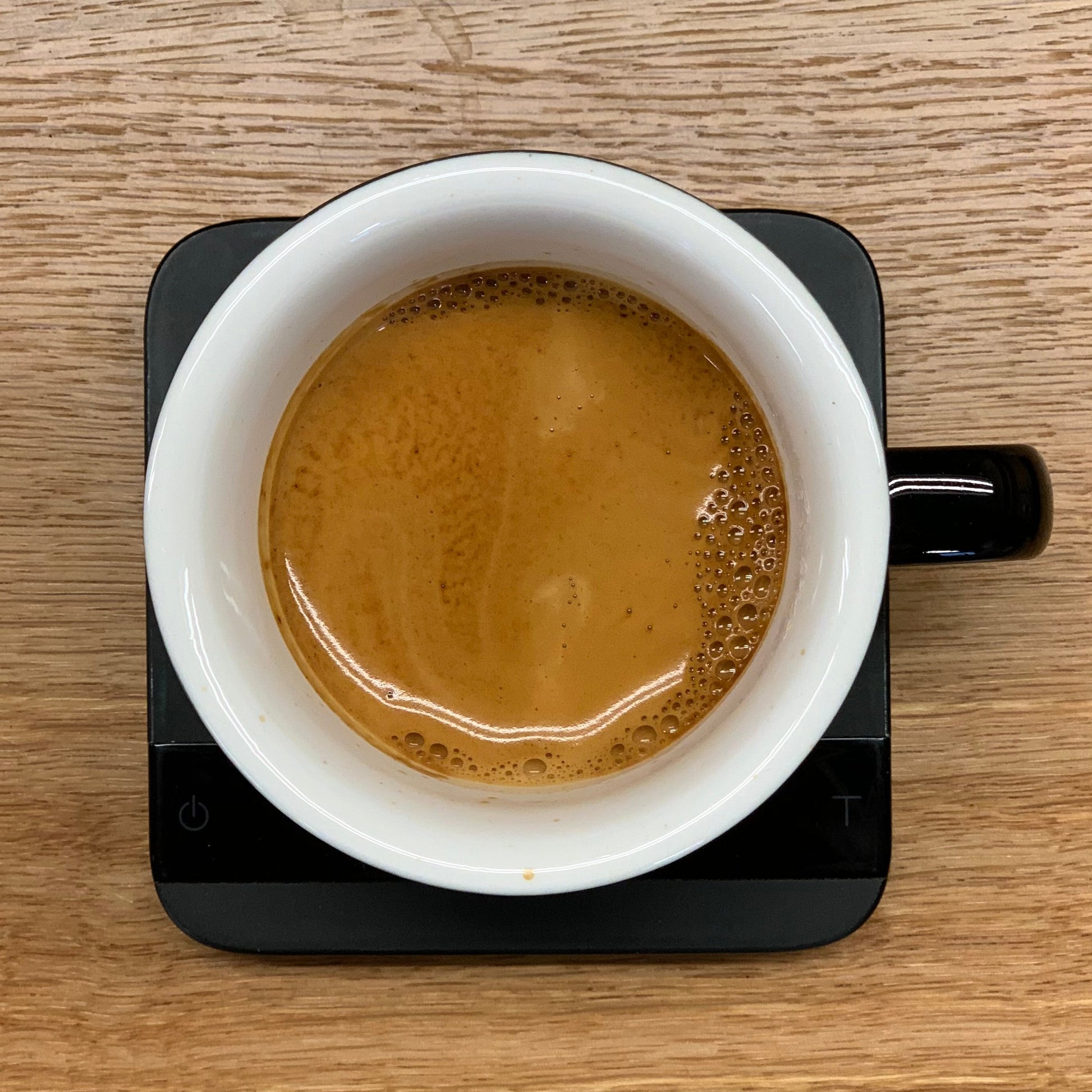 Overhead view of a ceramic espresso cup filled with freshly brewed coffee